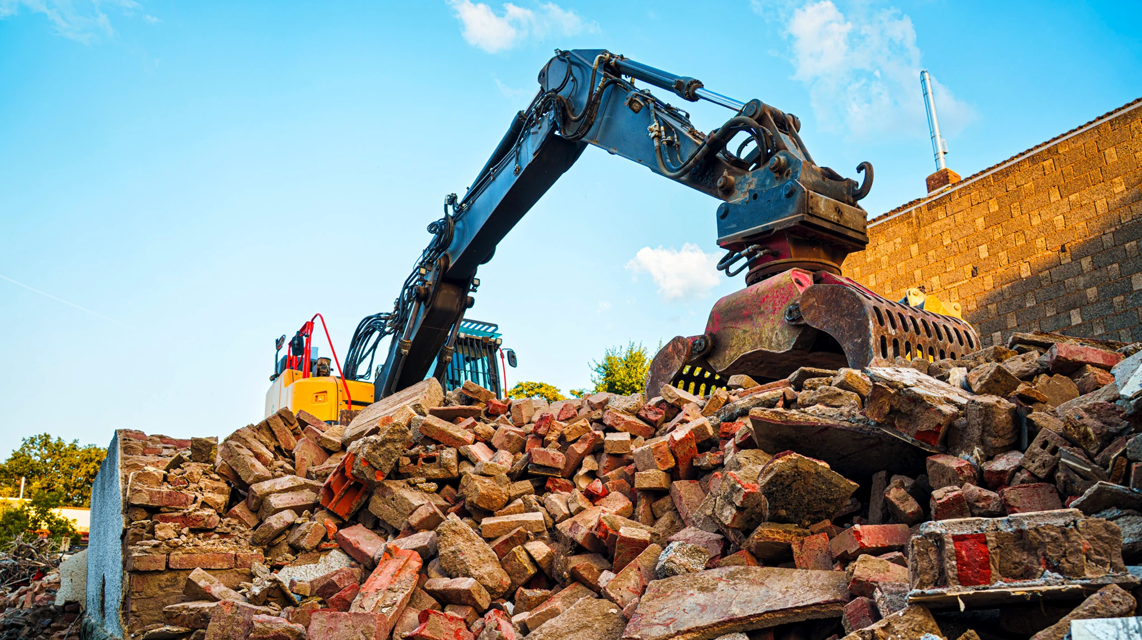 Scène de démolition résidentielle en extérieur avec pelleteuse CAT jaune en action