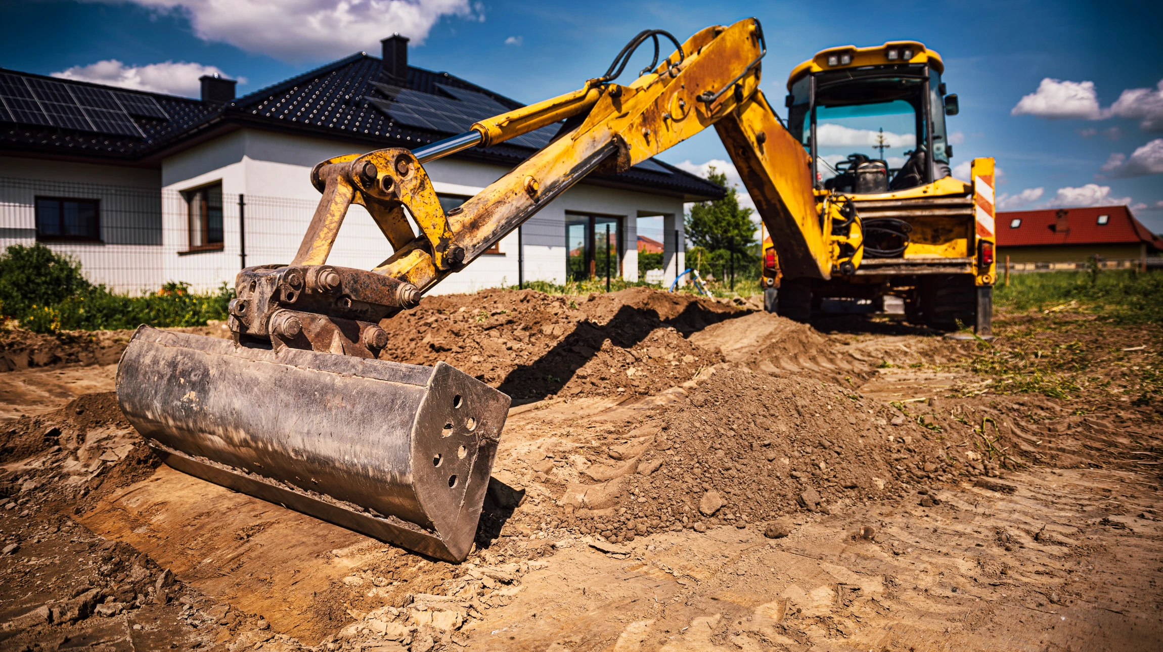 Chantier de terrassement en extérieur avec pelleteuse compacte jaune sur chenilles en fonctionnement