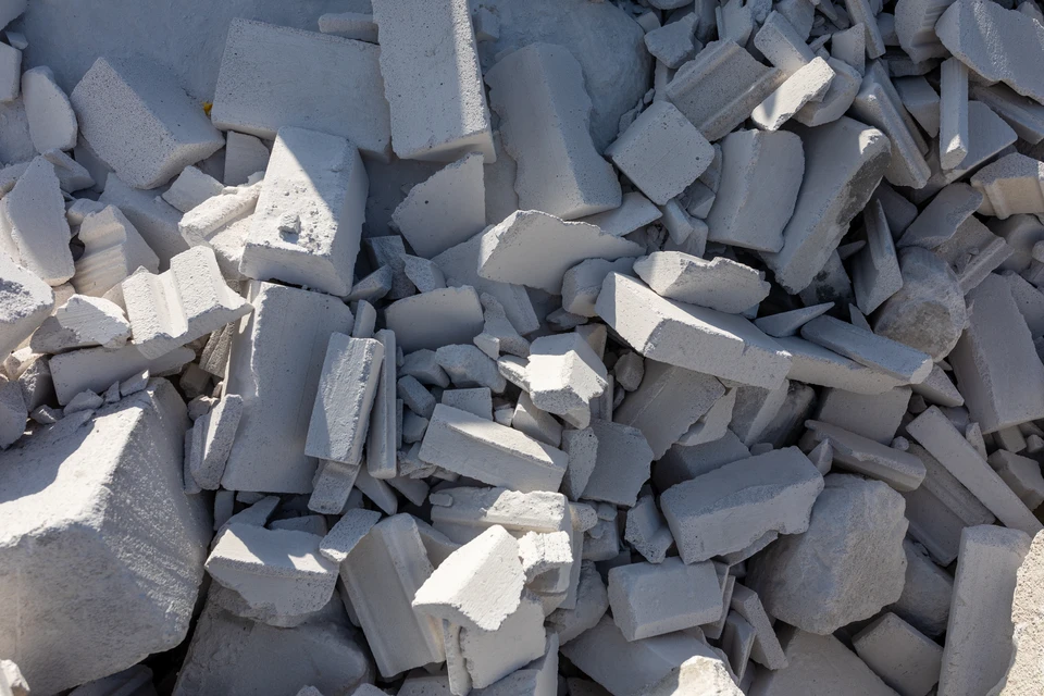 Scène extérieure sur pelouse verte avec main tenant une feuille de papier blanc découpée du symbole de recyclage triangulaire