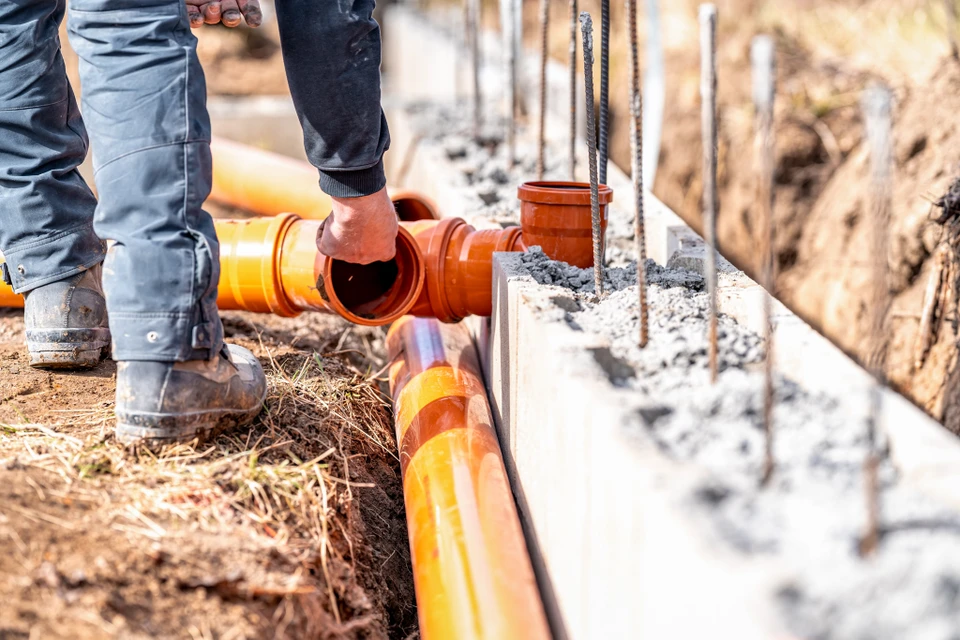 Terrain extérieur avec fosse septique en béton circulaire équipée d'un regard d'accès et d'un conduit de ventilation bleu PVC